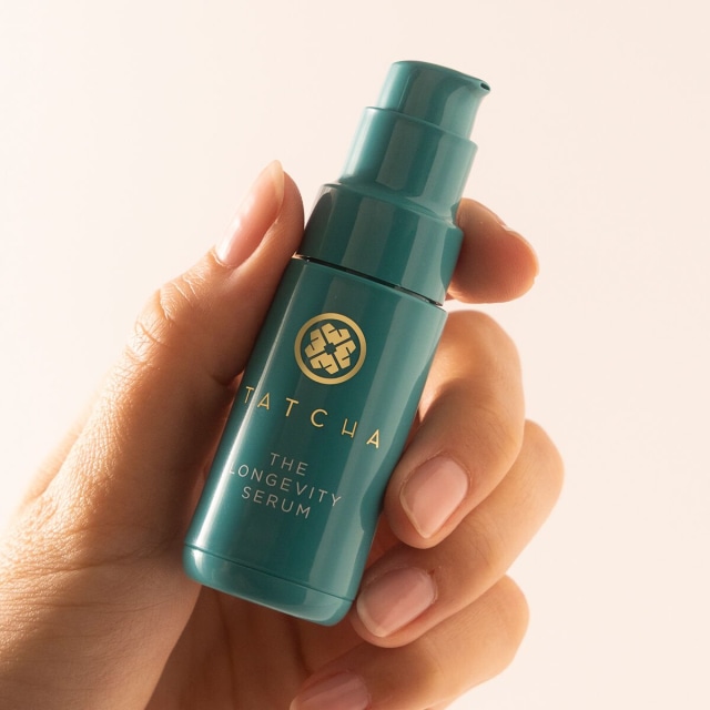 Shot of model applying The Longevity Serum onto face.